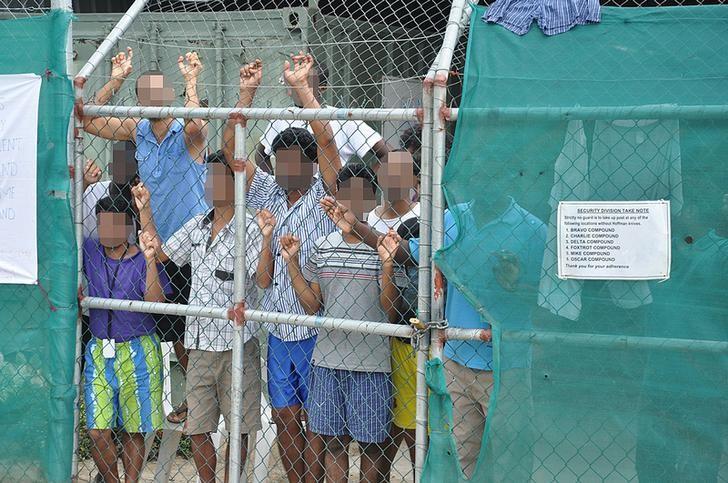 Asylum-seekers look through a fence at the Manus Island detention centre in Papua New Guinea